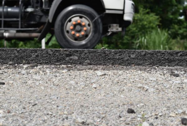 Bottom view of a heavy-duty truck unloading 1-inch Minus CAB in Southern California at a bustling road construction site.